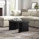 Lee oval black wood coffee table with intersecting panel legs styled in a bright living room