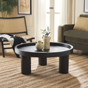 Dennis round black wood tray top coffee table with chunky cylinder legs styled in a living room