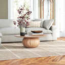 Nixon round natural wood coffee table with a spherical ball pedestal base styled in a bright living room