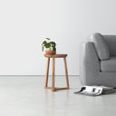 Martin light oak wood round end table with tapered tripod legs styled next to a couch