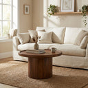 Paxton round dark walnut wood pedestal coffee table styled in a warm living room