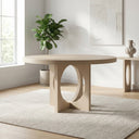 Loyal Round 6 Seater Dining Table in a natural wood finish styled in a bright modern dining room with a plant and neutral decor.