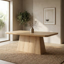 Langston Dining Table in natural wood finish styled in a warm modern dining room with a textured rug, decorative vase, and indoor olive tree.