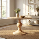 Hugh Round 6 Seater Dining Table in a light natural wood finish, featuring a round tabletop and ornate turned pedestal base in a bright, elegant dining room.