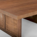 Close up angle view of Lachlan dark wood coffee table thick tabletop edge and woven cane legs