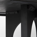 Close-up of the black Loyal dining table's curved tabletop edge and dark wood finish.