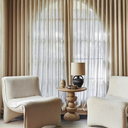 Mylo round wood side table styled between two cream boucle accent chairs in a living room