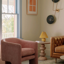 Mylo round wood side table styled in a colorful living room between a pink corduroy chair and tan leather sofa