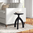Cillian round black solid wood end table with arched tripod legs styled in a living room
