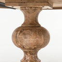 Close-up of the Hugh Dining Table’s carved pedestal, showcasing its rounded central form, decorative contours, and natural wood grain.