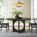 Black Loyal Round 6 Seater Dining Table styled in an elegant dining room with black chairs, greenery, pendant lighting, and neutral furnishings.