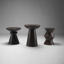 Three different Mercana dark brown solid wood sculptural accent tables shown together in a studio view
