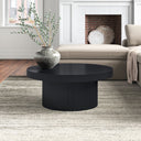 Bridger round black wood coffee table with ribbed pedestal drum base in a living room
