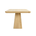 Straight-on view of the Langston Dining Table showing its thick tabletop and wide trapezoidal pedestal base.