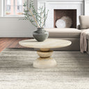 Musa round light wood coffee table with stacked geometric pedestal base in a modern living room