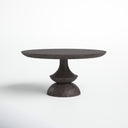 Studio view of the dark Musa dining table featuring a broad round tabletop and distinctive hourglass-inspired pedestal base.