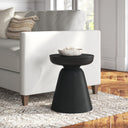 Matte black concrete drum end table with pedestal base styled next to a couch