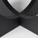 Detailed close-up of the black Loyal dining table's intersecting curved pedestal panels and wood construction.