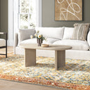Lee oval light oak wood coffee table with intersecting panel legs styled in a living room