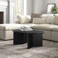 Lee oval black wood coffee table with intersecting panel legs styled in a bright living room