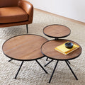 Cayden Side Table set of three round wood-top tables with black tripod legs arranged on a living room rug.