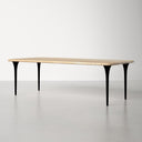 Front view of the Landyn Solid Dining Table highlighting its long natural wood tabletop and distinctive slender black legs.