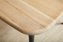 Detailed view of a Landyn Dining Table corner highlighting the rounded solid wood tabletop edge and sculpted black tapered leg.
