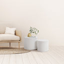 Cohen End Table set featuring two white cylindrical tables beside a neutral upholstered chair.