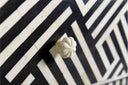 Macro view of Reign drawer front showing chevron bone inlay texture and carved flower knob