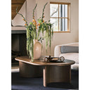 Louie oval walnut wood coffee table styled in an upscale living room with a large ceramic floral vase