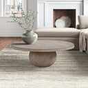 Chaim round light wood coffee table with spherical pedestal sphere base in a cozy living room