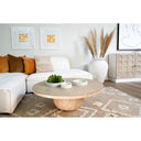 Chaim round light wood coffee table styled in a complete living room scene with a white sectional sofa and geometric rug