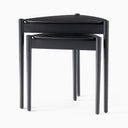 Close-up of Lewis Tripod Nesting Side Tables showing the black wood-grain tabletops, rounded edges, and cylindrical legs.