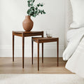 Lewis Tripod Nesting Side Tables in a living room beside a gray sofa, featuring rounded black tabletops and slender tripod-style legs.