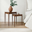 Lewis Tripod Nesting Side Tables in a living room beside a gray sofa, featuring rounded black tabletops and slender tripod-style legs.