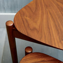 Detailed view of the Lewis Tripod Nesting Side Tables highlighting the smooth black tabletop, rounded edge, and tripod-style leg construction.