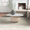 Cason round coffee table with white marble top and spherical wood ball pedestal base in a living room