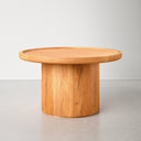 Paxton round wood pedestal coffee table side view showcasing cylindrical drum base