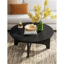 Alternative styled living room view of Skyler round black wood coffee table with a green vase
