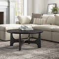 Skyler round black wood coffee table with cross arched pedestal base styled in a living room
