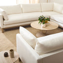Leandro round natural wood coffee table styled in a complete living room with an ivory sectional sofa