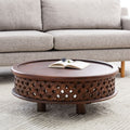 Chandler round carved wood coffee table with lattice fretwork apron base styled in a living room