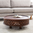 Chandler round carved wood coffee table with lattice fretwork apron base styled in a living room
