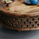 Close up angle view of Chandler coffee table showing natural carved lattice fretwork and playing cards