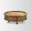 Chandler round natural carved wood coffee table three-quarter studio view showcasing lattice fretwork apron base