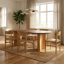 Kiaan Oval 6 Seater Dining Table in natural finish displayed in a contemporary dining room with a neutral rug, large windows, and decorative centerpiece.