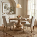 Musa Round Dining Table styled with upholstered dining chairs, a fruit bowl and neutral decor in an elegant contemporary interior.