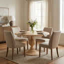 Hugh Round Dining Table in a dark brown wood finish, featuring a smooth circular top and intricately turned pedestal base in a refined living space.