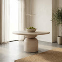 Tomas Round 6 Seater Dining Table with a light natural wood finish and sculptural pedestal base in a bright modern dining space.