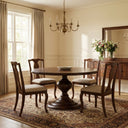 Hugh Round Dining Table presented in a bright dining setting, featuring a natural wood pedestal design and a round tabletop arranged for six.